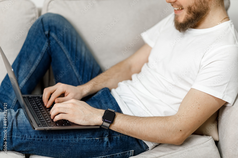 close-up of a man working on a laptop at home on the couch. no face. close-up of a man working on a laptop at home on the couch. no face.