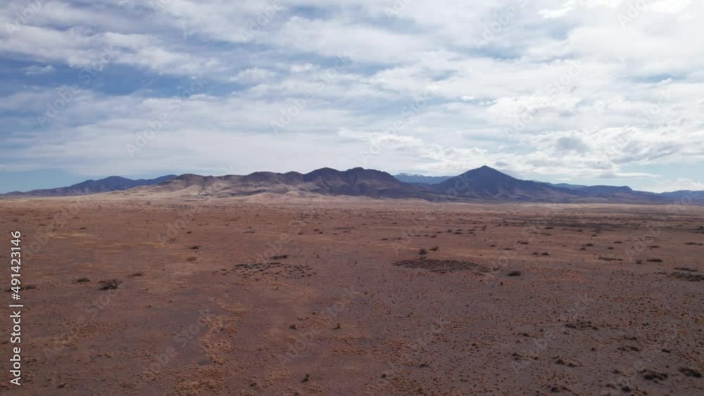 Drone shot flying over the desert towards a large mountain range, NM Drone shot flying over the desert towards a large mountain range, NM