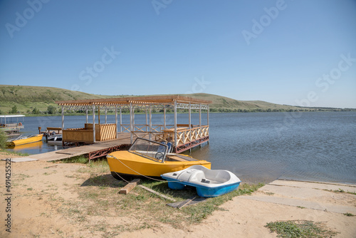 A small sandy beach on a pond with a pier and pleasure boats. Eastern Europe, summer, clear weather.