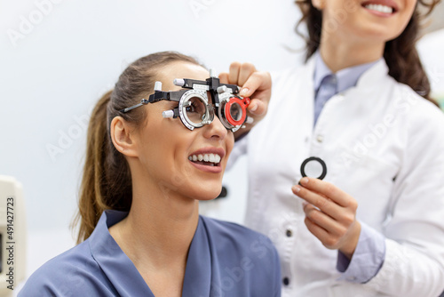 Ophthalmologist examining woman with optometrist trial frame. female patient to check vision in ophthalmological clinic photo