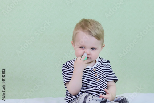 A defocused infant uses a nasal aspirator into the nose, sucking out the mucus. Cleansing snot in a child. Copy space - concept of health, colds, immunity, prevention, parental love, cure photo