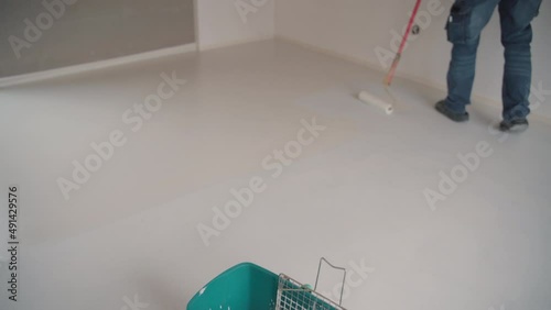 Construction worker performs floor screed indoors. Self-priming freshly prepared floor. 4K