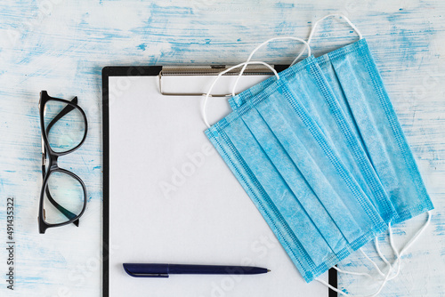 Medical protective masks and glasses with pen on doctor's tablet