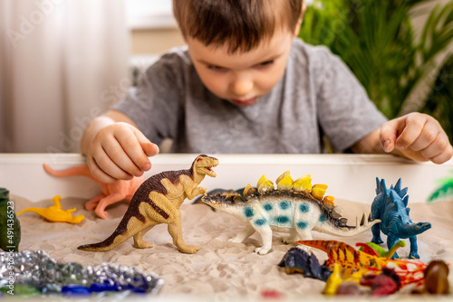 Confident cute baby boy playing carnivorous and herbivorous dinosaurs early development game photo