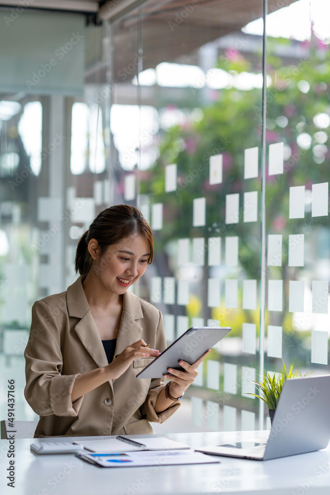 Fototapeta premium Smiling Asian girl student write on the tablet to study language online watch and listen to the lecturer, webinar via video call e-learning at home, distance education