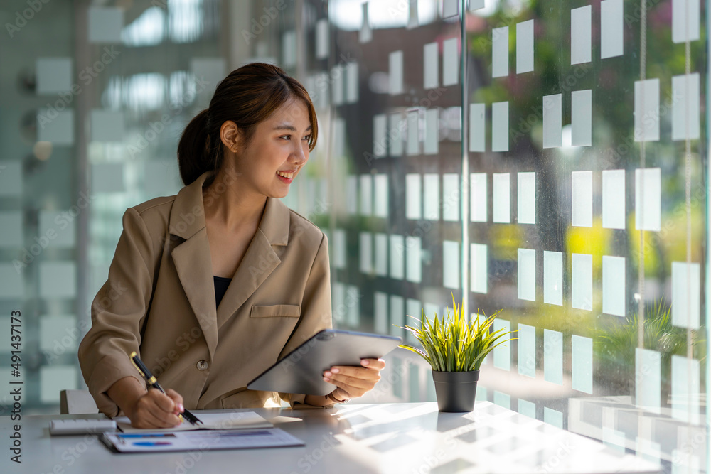 Charming Asian woman working at the office using a tablet. Charming Asian woman working at the office using a tablet.