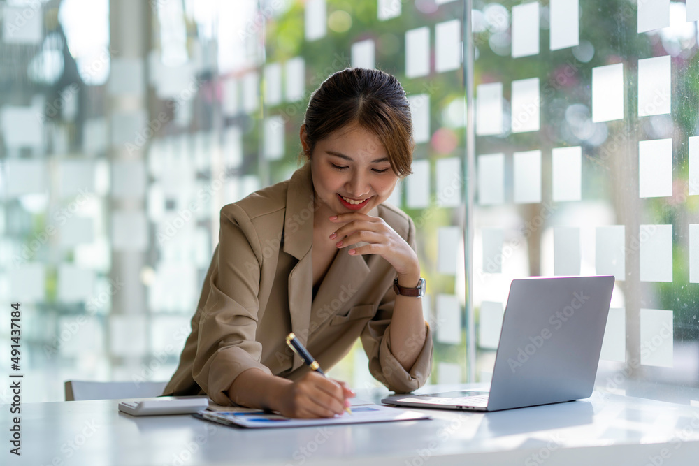 Fototapeta premium Charming asian businesswoman sitting working on laptop in office.