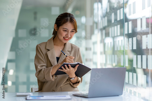 Charming asian businesswoman sitting working on laptop in office.