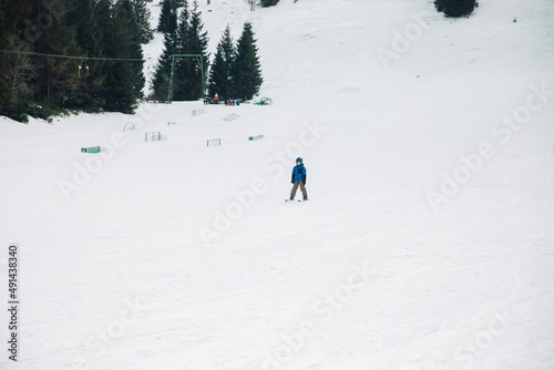 Little boy in a ski suit, goggles and helmet is skiing on the ski slope. Ski vacation during vacation. children's skis 