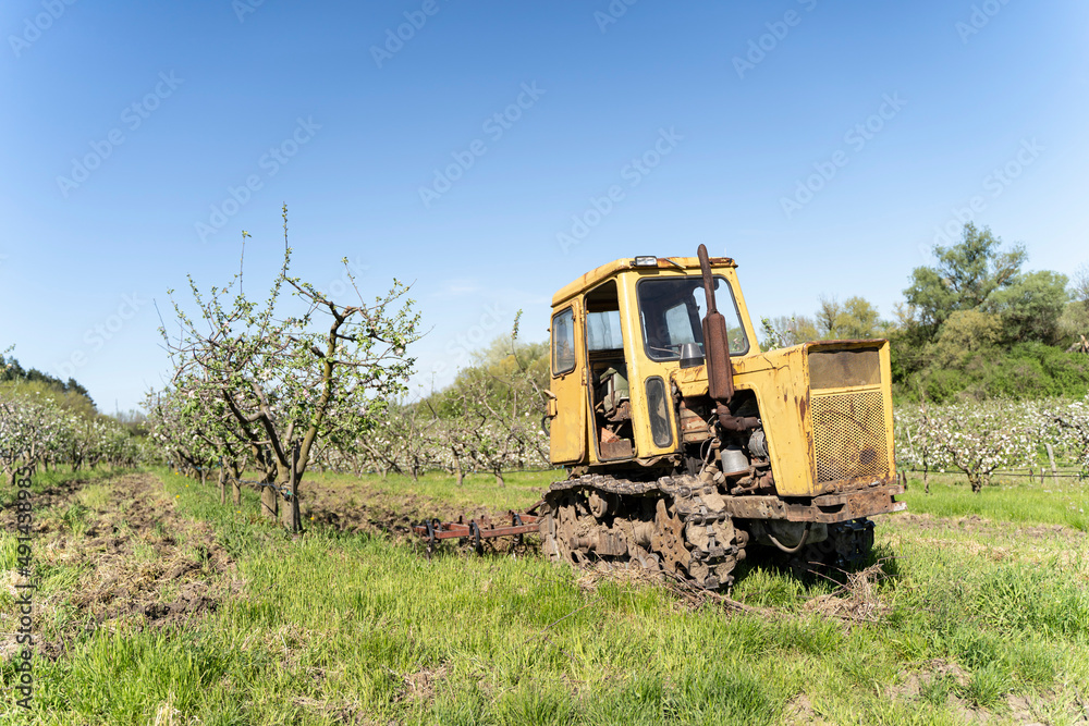 Old Tractor in the Field. Farmer in Old-fashioned tractor sowing crops at field. Woman driving small tractor in field and waving hand