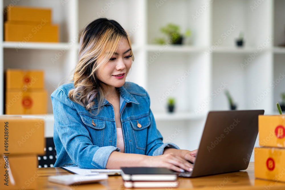 Starting Small business entrepreneur SME freelance,Portrait young woman working at home office, BOX,smartphone,laptop, online, marketing, packaging, delivery, SME, e-commerce concept Starting Small business entrepreneur SME freelance,Portrait young woman working at home office, BOX,smartphone,laptop, online, marketing, packaging, delivery, SME, e-commerce concept