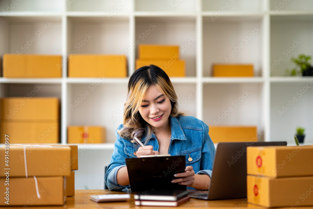 Starting Small business entrepreneur SME freelance,Portrait young woman working at home office, BOX,smartphone,laptop, online, marketing, packaging, delivery, SME, e-commerce concept. Starting Small business entrepreneur SME freelance,Portrait young woman working at home office, BOX,smartphone,laptop, online, marketing, packaging, delivery, SME, e-commerce concept.