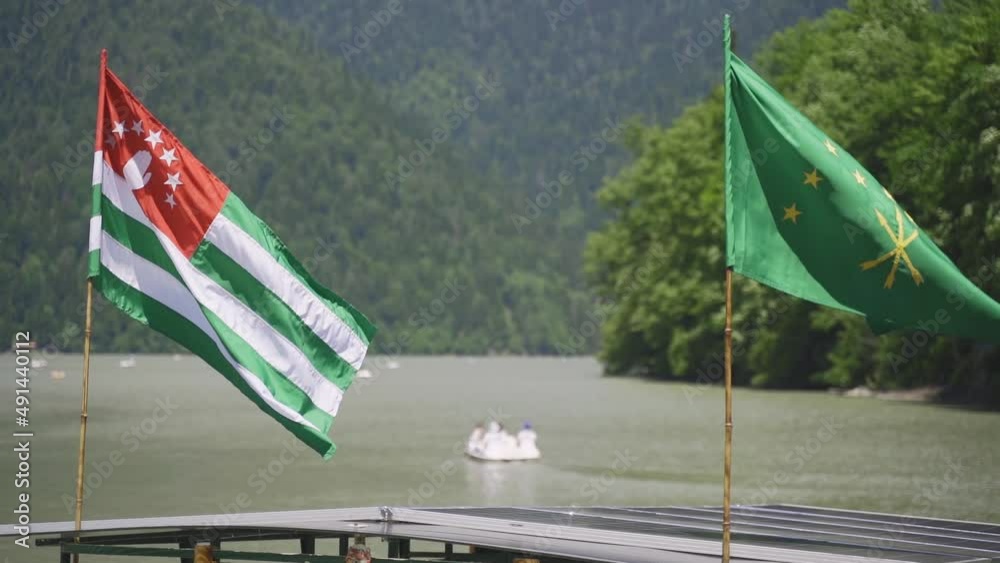 The state flag of the country of Abkhazia and Adygea against the background of the beautiful Lake Ritsa The state flag of the country of Abkhazia and Adygea against the background of the beautiful Lake Ritsa