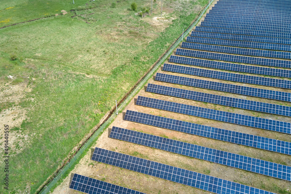 Aerial view of solar power plant on green field. Electric farm with panels for producing clean ecologic energy