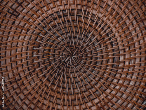 Beautiful pattern on handmade woven basket. Detail of wicker artwork background with circle structure. Texture of round traditional crafted handicrafts rattan tray. Natural brown bamboo furniture