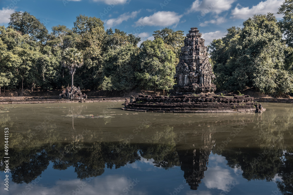 Ruins of ancient Cambodian temple among trees on lake in Angkor complex, Siem Reap, Cambodia