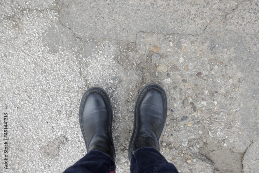 Person in chunky platform leather boots on asphalt, top view Person in chunky platform leather boots on asphalt, top view