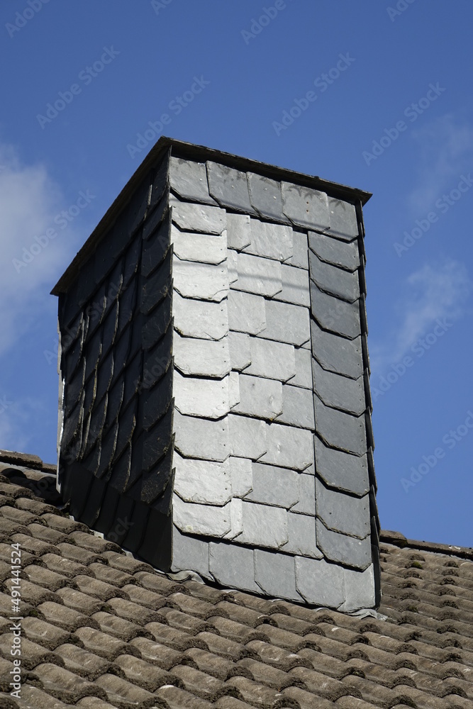 Chimney of Siegerland house with black slate shingles, clear blue winter sky, low angle view, concept: heating, fossil fuel, gas shortage, c02 footprint (vertical), Dahlbruch, NRW, Germany Chimney of Siegerland house with black slate shingles, clear blue winter sky, low angle view, concept: heating, fossil fuel, gas shortage, c02 footprint (vertical), Dahlbruch, NRW, Germany