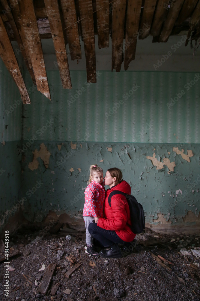 Mother and her daughter in destroyed buildng. War, refugees, war crisis concept.