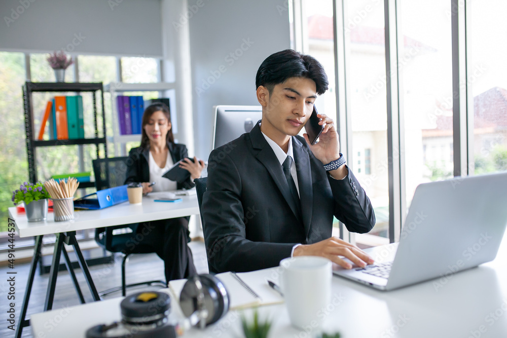 Portrait of Asian handsome man working at the office, using smartphone and computer on table. Portrait of Asian handsome man working at the office, using smartphone and computer on table.