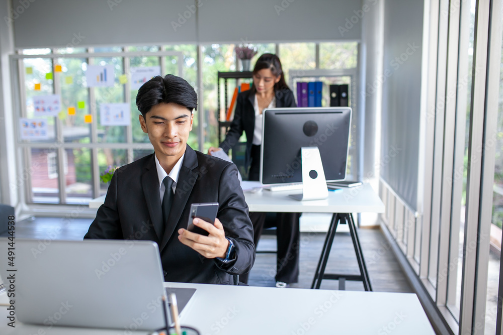 Portrait of Asian handsome man working at the office, using smartphone and computer on table. Portrait of Asian handsome man working at the office, using smartphone and computer on table.
