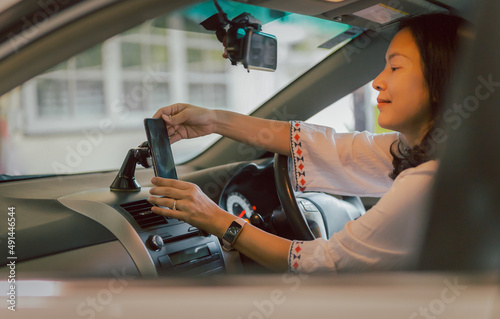 Woman driver hand adjust cell phone in stand holder for direction. photo