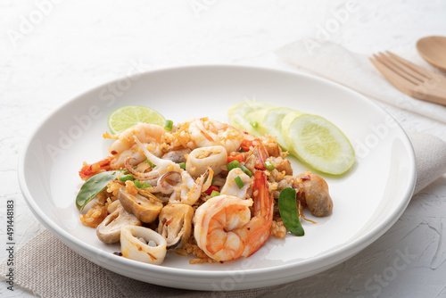 Seafood Tom Yum Fried Rice,Stir fried rice with shrimp squid and straw mushroom with sauce on white plate