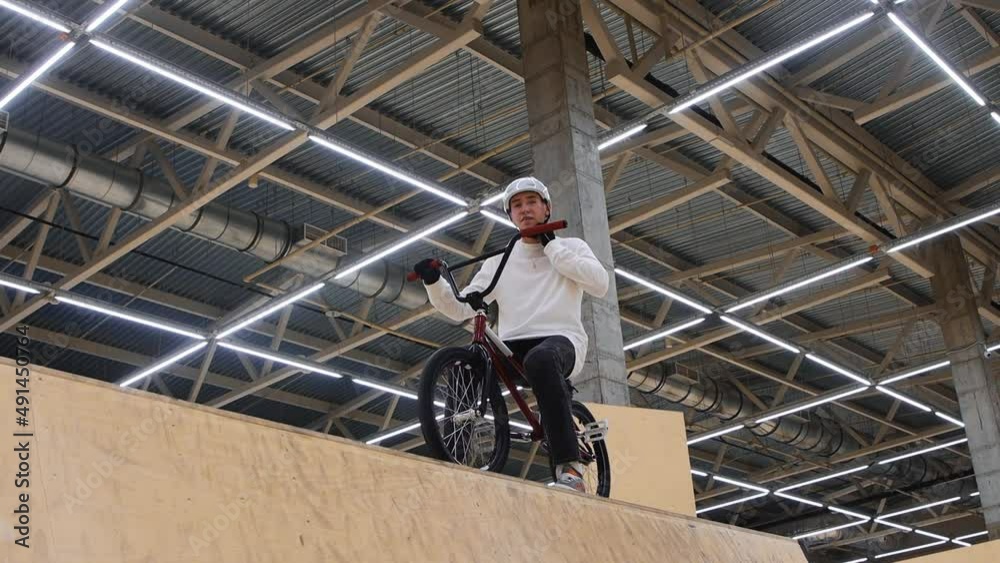 BMX sports - young man riding on the top of the springboard and takes off his helmet BMX sports - young man riding on the top of the springboard and takes off his helmet
