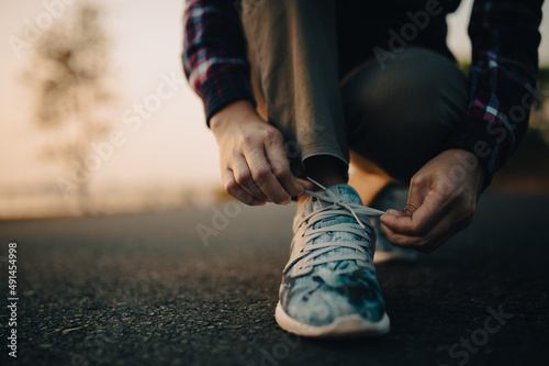 young woman tying her shoelaces at sunset.