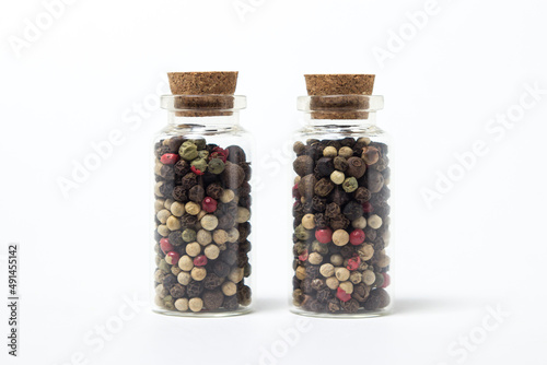 A mixture of peppercorns in a glass flask on a white background. Hot peppercorns.