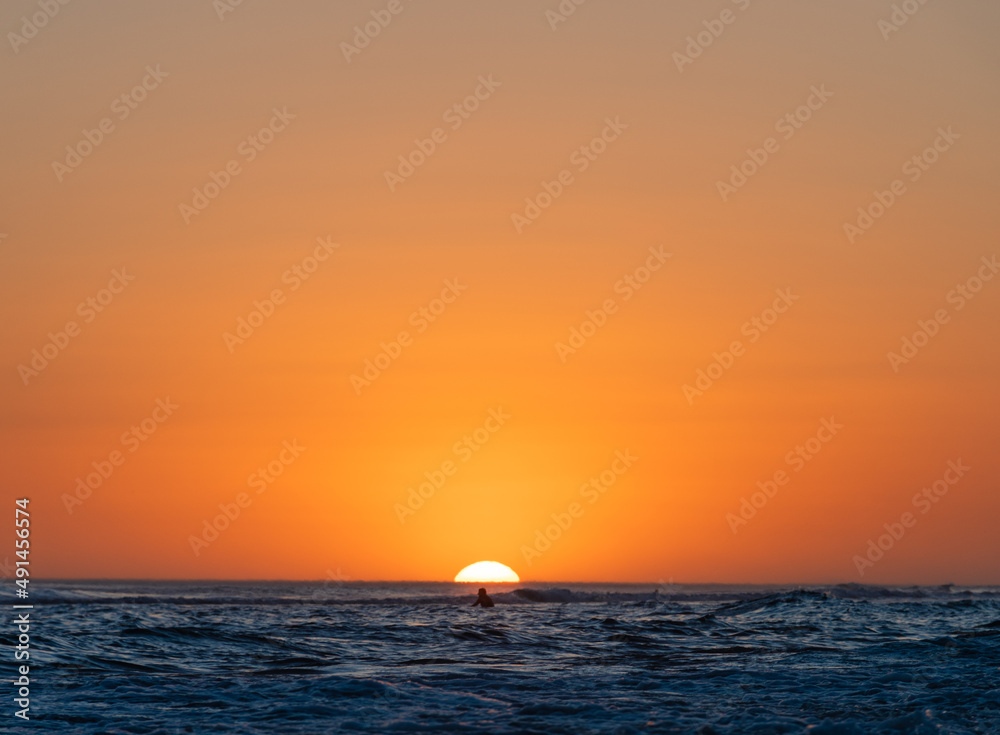 Silhouette of a person alone in the sea during a colorful sunset on the beach. Silhouette of a person alone in the sea during a colorful sunset on the beach.
