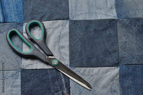 scissors lying on top of a canvas sewn from pieces of denim.