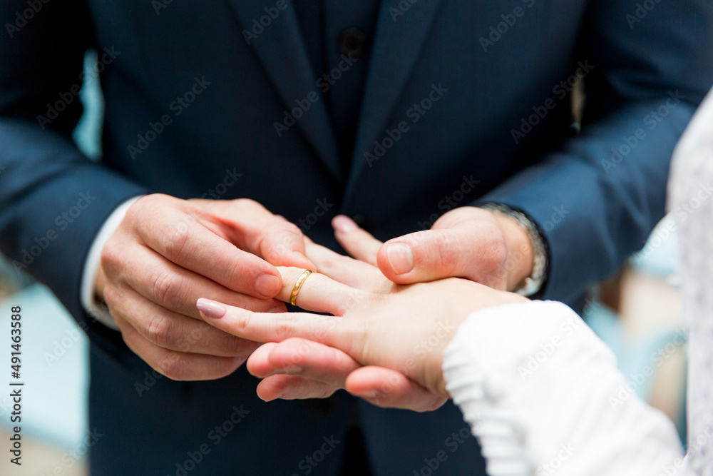 groom putting wedding ring on bride holding hands