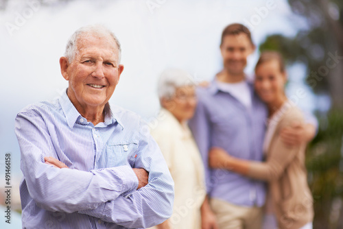 Hes happy with his life. Portrait of a smiling mature man with his family in the background.
