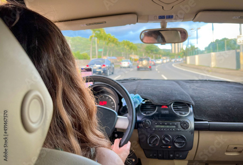 Woman driving in Hawaii, USA. View from inside the vehicle. Young woman is driving a car. A day with traffic