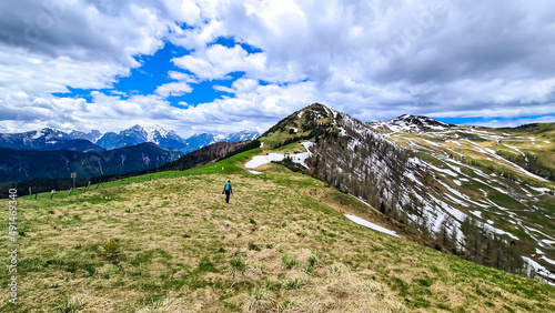 Hiker woman with backpack at summit of Hahnkogel (Klek) with scenic view on mountain peaks in Karawanks and Julian Alps, Carinthia, Austria. Border with Slovenia. Triglav National Park. Goal seeking photo