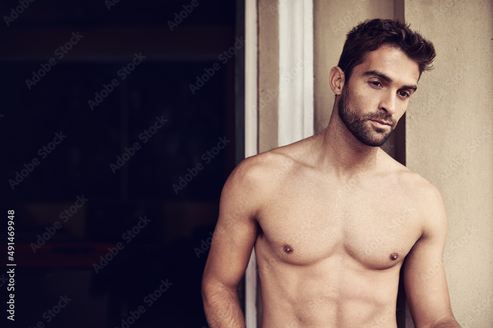 Hes a mans man. Cropped shot of a shirtless young man at home. Hes a mans man. Cropped shot of a shirtless young man at home.