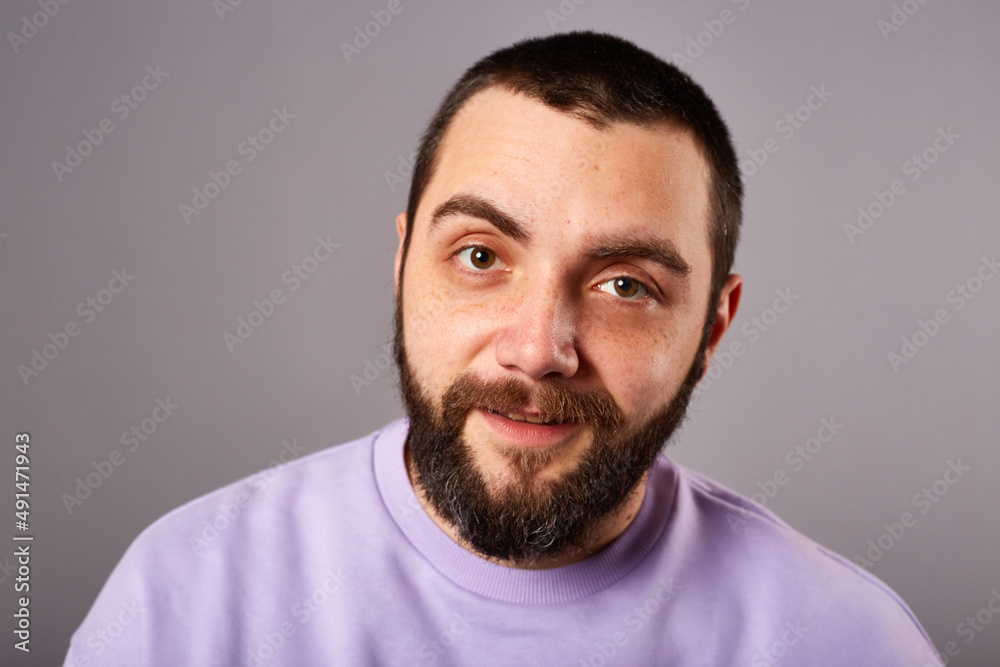funny bearded man wears violet sweater on grey background