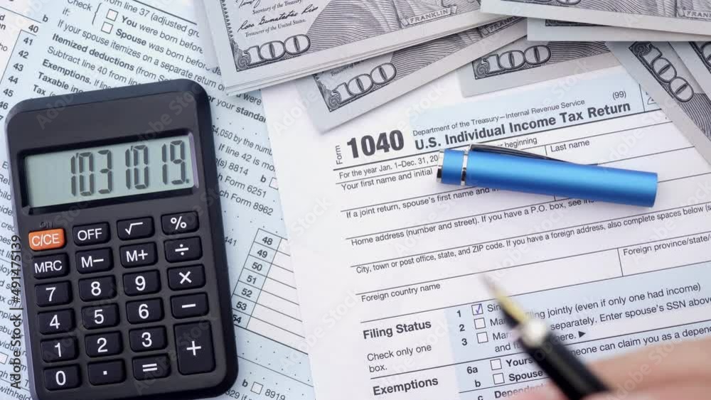 Tax form 1040, pen, dollar bills, and calculator. High angle view. Tax form 1040, pen, dollar bills, and calculator. High angle view.