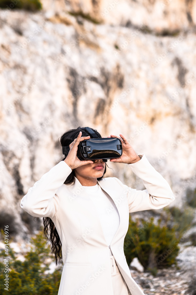 Una elegante mujer vestida con un traje blanco usando unas gafas de realidad virtual Una elegante mujer vestida con un traje blanco usando unas gafas de realidad virtual
