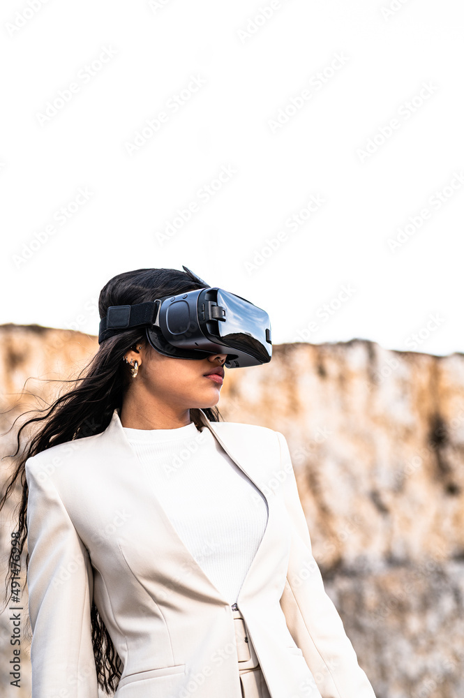Una elegante mujer vestida con un traje blanco usando unas gafas de realidad virtual Una elegante mujer vestida con un traje blanco usando unas gafas de realidad virtual