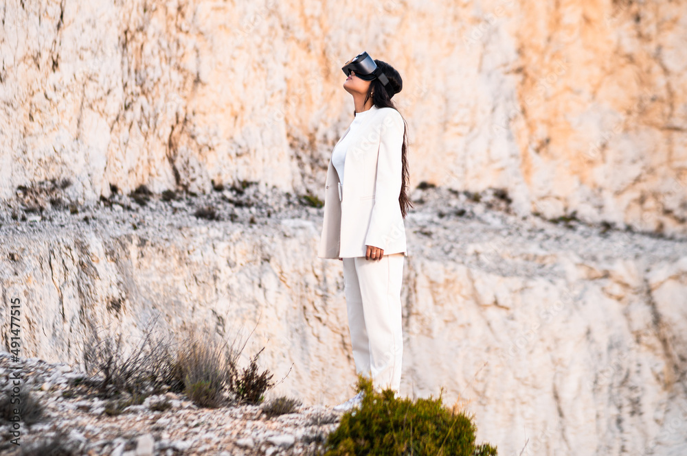 Una elegante mujer vestida con un traje blanco usando unas gafas de realidad virtual