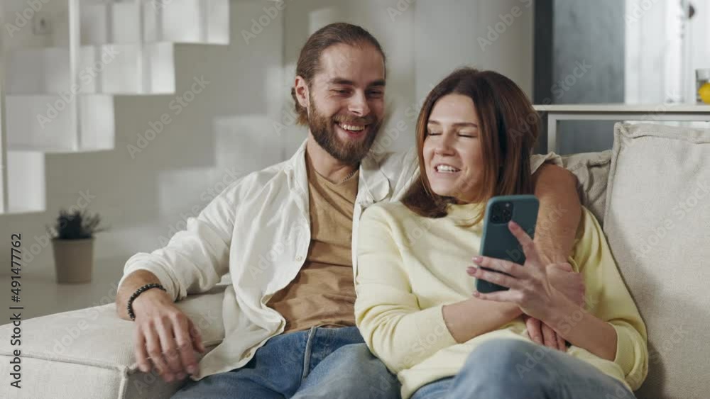 Positive family sitting on couch with smartphone in hands Positive family sitting on couch with smartphone in hands