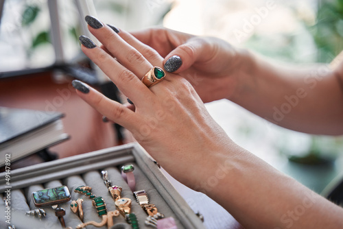 Woman trying on beautiful ring and looking at her hands while creating her look at home