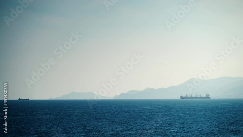 Seascape with cargo container industrial ship anchored waiting for entering Carboneras port in Almeria, Spain. Mediterranean sea coast.