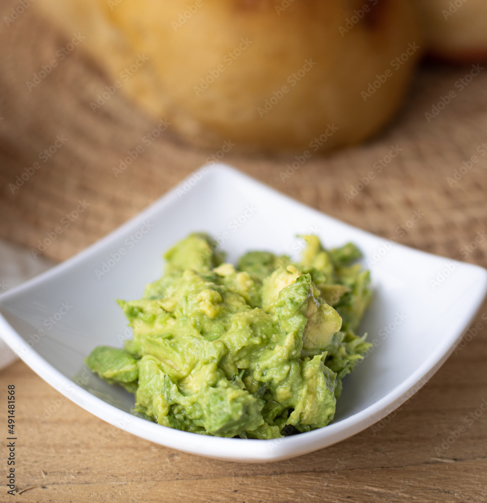 Close up of guacamole dip in bowl over yellow background with free text space. Healthy avocado spread. Top view, flat lay Close up of guacamole dip in bowl over yellow background with free text space. Healthy avocado spread. Top view, flat lay