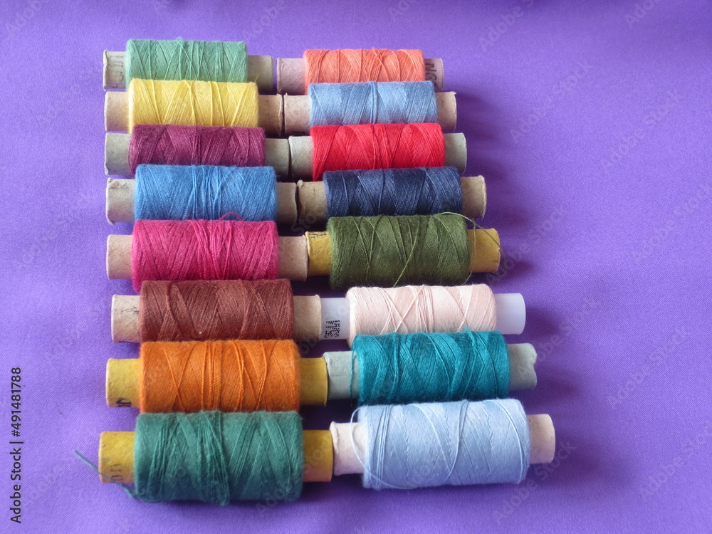 Spools of thread of different colors are stacked in a row. Multicolored threads for sewing. Spools of thread of different colors are stacked in a row. Multicolored threads for sewing.