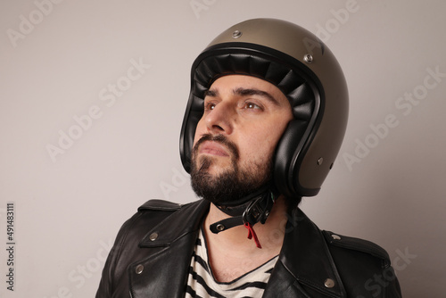 Bearded biker man posing in leather jacket and motorcycle helmet looking aside. © face_reader_img