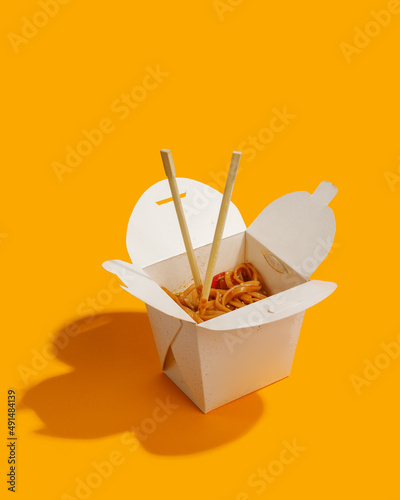 wok noodles in paper box fast food yellow background