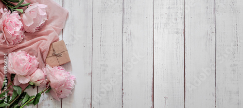 Fototapeta Naklejka Na Ścianę i Meble -  Spring, summer floral still life with copy space. Close-up of pink peonies on a white wooden background. Rustic style web banner. Flat lay, top view.